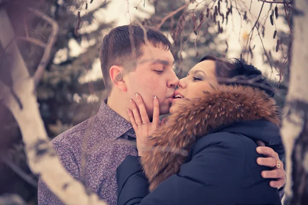 Casal jovem beijando na floresta de inverno — Fotografia de Stock