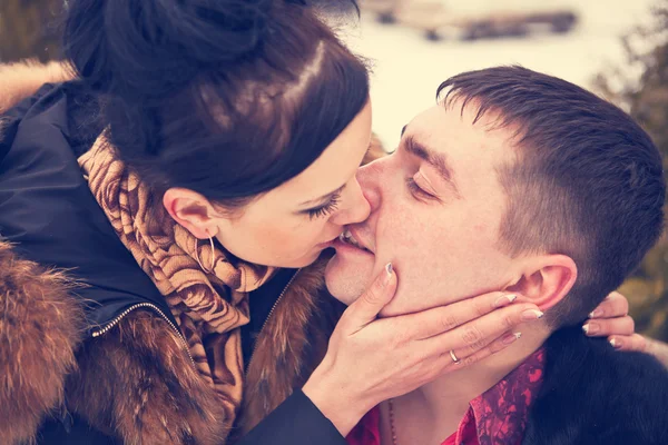 Casal jovem beijando na floresta de inverno — Fotografia de Stock