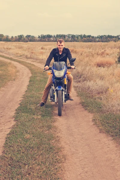 Man with a motorcycle on a country road — Stock Photo, Image
