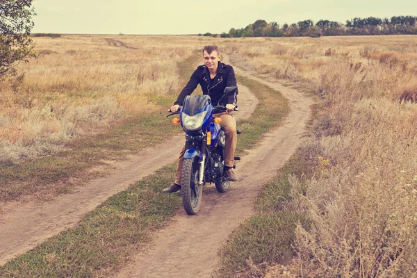 Man with a motorcycle on a country road — Stock Photo, Image