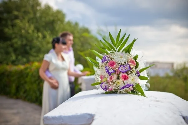 Bridal bouquet on the background defocused young couples — Stock Photo, Image