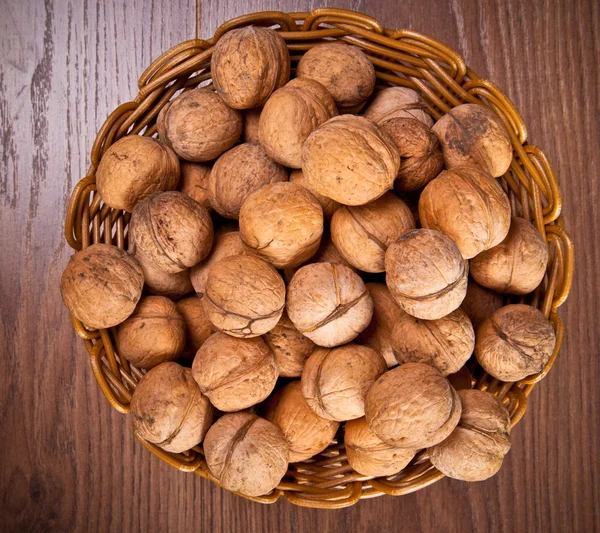 Noix dans un panier en osier sur un fond en bois — Photo