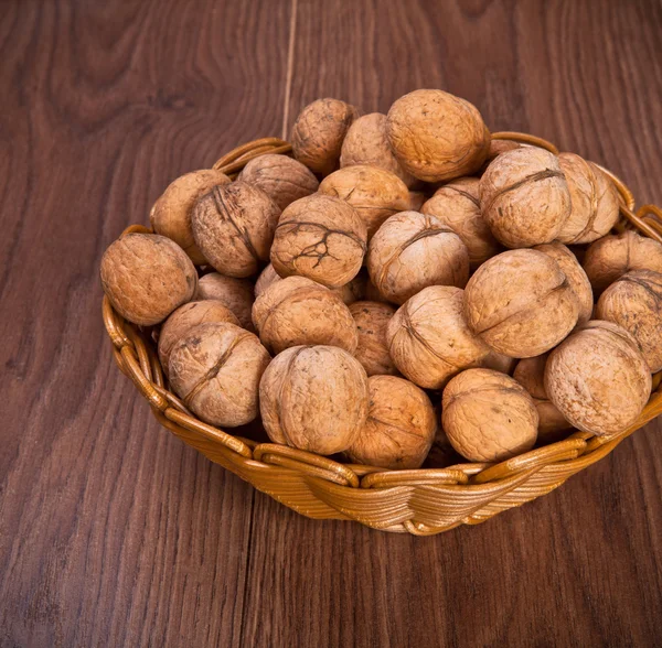 Walnuts in a wicker basket on a wooden background — Stock Photo, Image