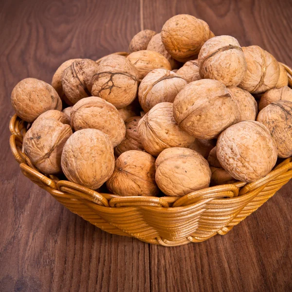 Walnuts in a wicker basket on a wooden background — Stock Photo, Image