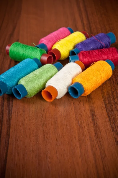 Colorful spools of thread on a wooden background — Stock Photo, Image