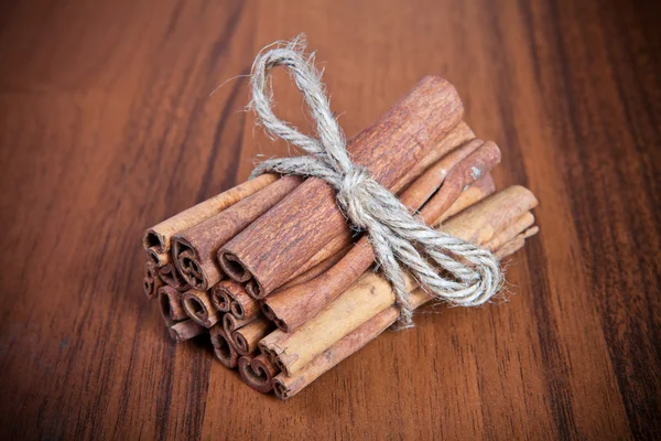 Bâtons de cannelle connexes sur fond en bois — Photo