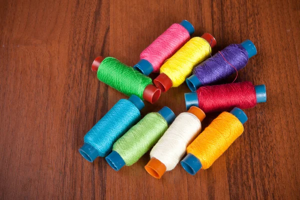 Carretes coloridos de hilo sobre un fondo de madera — Foto de Stock