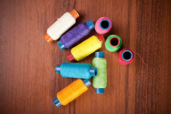 Colorful spools of thread on a wooden background — Stock Photo, Image