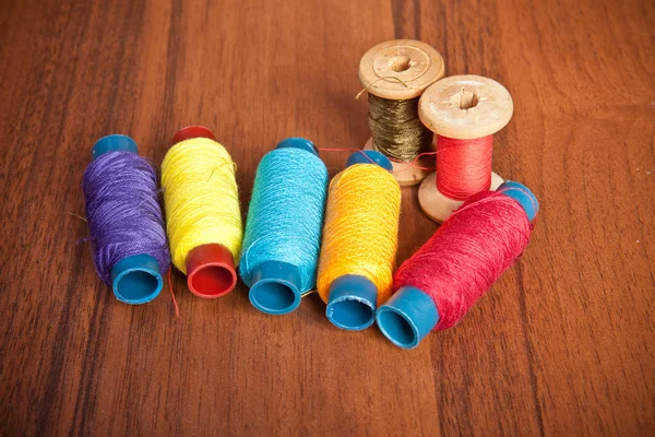 Colorful spools of thread on a wooden background — Stock Photo, Image