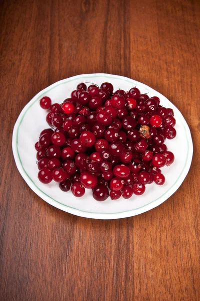 Cranberries em um pires em um fundo de madeira — Fotografia de Stock