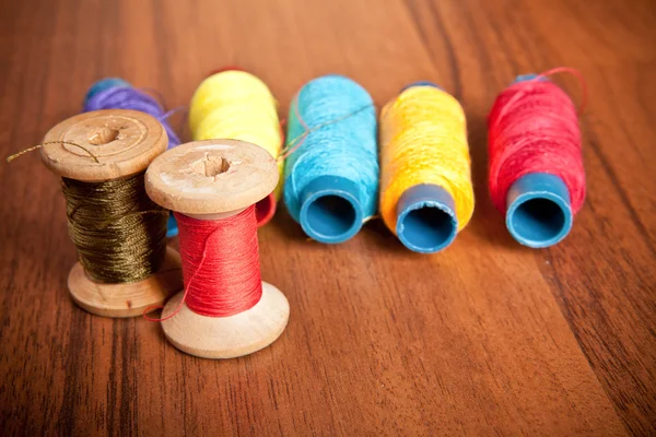 Carretes coloridos de hilo sobre un fondo de madera — Foto de Stock