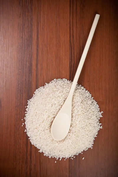Vařečka na kopci rýže na dřevěné pozadí — Stock fotografie
