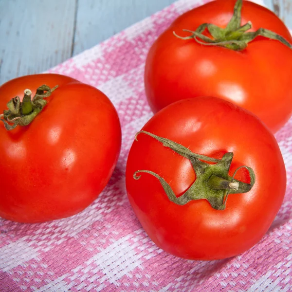 Drie tomaten op een geruite handdoek — Stockfoto