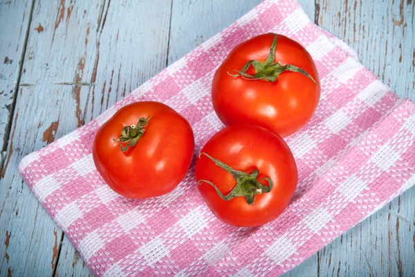 Três tomates em uma toalha de xadrez — Fotografia de Stock