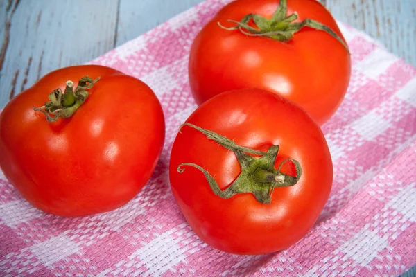 Three tomatoes on a plaid towel — Stock Photo, Image