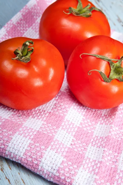 Três tomates em uma toalha de xadrez — Fotografia de Stock