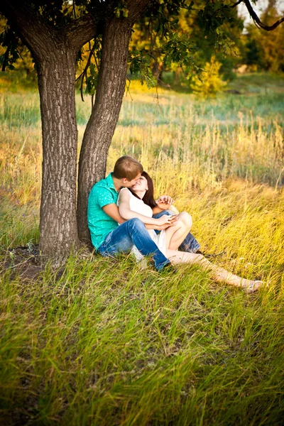 Pareja joven besándose bajo un árbol — Foto de Stock