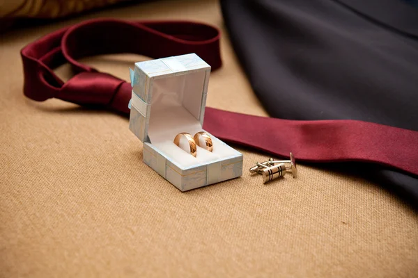 Wedding rings, cufflinks tie on the couch — Stock Photo, Image