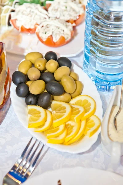 Olives and lemon slices on a plate — Stock Photo, Image