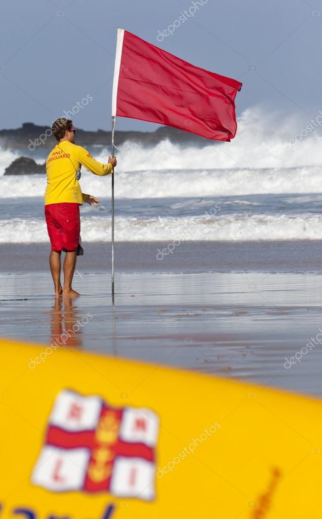 ST IVES, UK - September 11 : A lifeguard from the Royal National Lifeboat Institution on Porthmeor beach in St Ives, Cornwall on 11th September 2011. The flag warns swimmers not to enter the water.
