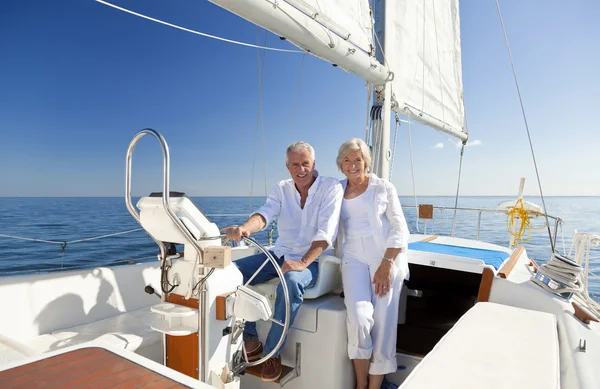 Una coppia anziana felice seduta al volante di una barca a vela — Foto Stock