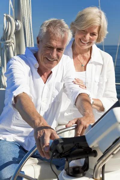 A happy senior couple sitting at the wheel of a sail boat — Stock Photo, Image