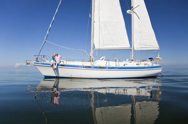 Um feliz casal sénior sentado na frente de um barco à vela — Fotografia de Stock