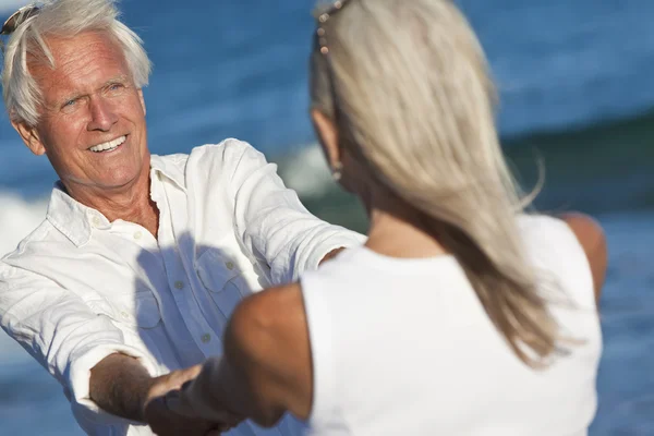 Heureux couple âgé dansant tenant la main sur une plage tropicale — Photo