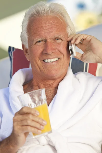 Hombre mayor guapo hablando en el teléfono celular bebiendo jugo de naranja — Foto de Stock