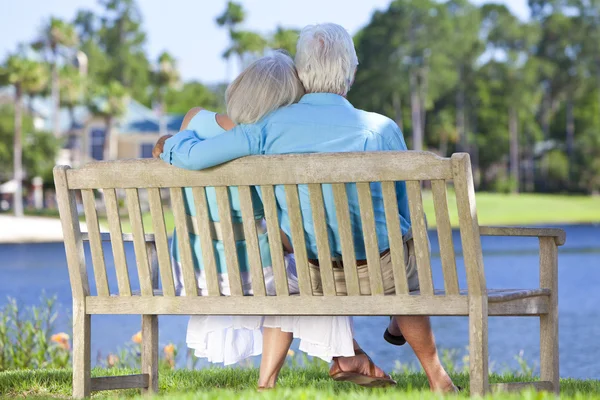 Bakifrån äldre par sitter på park bänk omfattar — Stockfoto