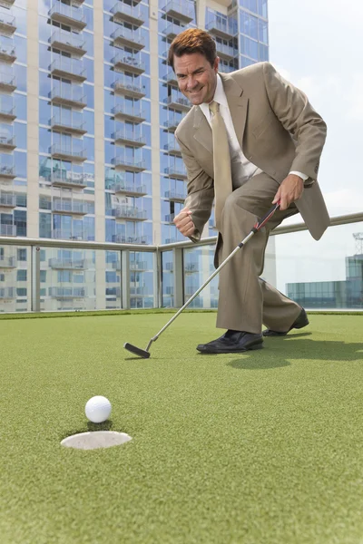Empresario exitoso jugando golf en la azotea del rascacielos — Foto de Stock