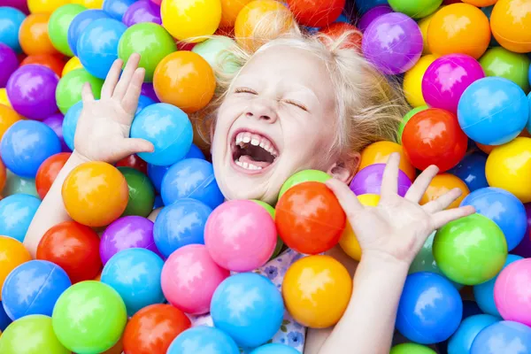 Блондинка ребенок весело играет в цветные шарики — стоковое фото
