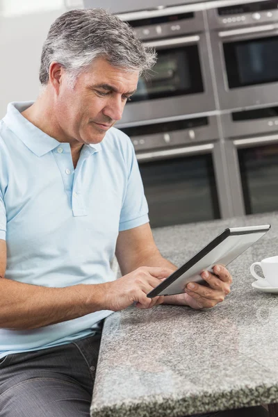 Человек с помощью планшетного компьютера на кухне питьевой кофе — стоковое фото