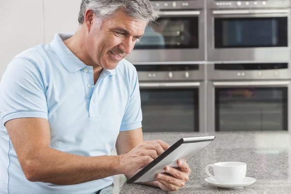 Mann benutzt Tablet-Computer in Küche und trinkt Kaffee — Stockfoto