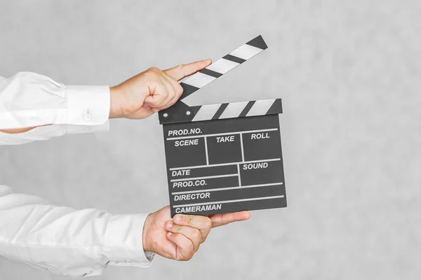 The director\'s clapperboard is in the hands of a man. On a light background