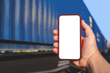 Bir adamın elinde telefon modeli var. Bir tren vagonunun arka planında