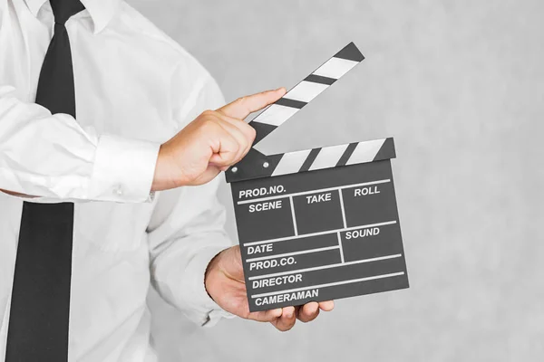 The director\'s clapperboard is in the hands of a man. On a light background