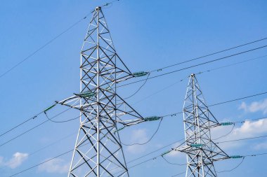 Elektrik hatları ve kuleler - modern bir enerji sistemi. Arkaplanda bulutlu mavi bir gökyüzü