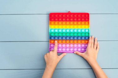 Yakından bakınca, çocuk elinde popüler bir oyuncak baloncuğu tutuyor. Patlat bakalım, anti-stres. Gri bir arkaplanda