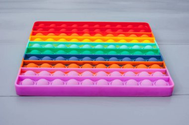 Yakın plan, parlak renkli silikon patlat onu oyuncak. Gri arka planda popüler anti-stres oyuncağı