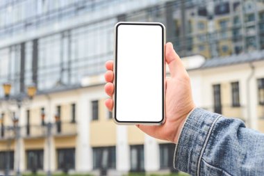 Yakın plan, akıllı telefonun bir erkeğin elinde mokasenti. Bir cam iş merkezinin arka planına karşı