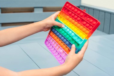 Yakından bakınca, çocuk elinde popüler bir oyuncak baloncuğu tutuyor. Patlat bakalım, anti-stres. Gri bir arkaplanda