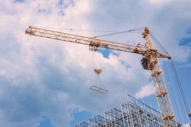 İnşaat vinci ve yeni çelik bir yapı. Arkaplanda bulutlu mavi bir gökyüzü