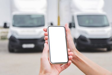 Kadın ellerinde akıllı telefon modeliyle. Kamyonların arka planına karşı. Lojistik kavramı