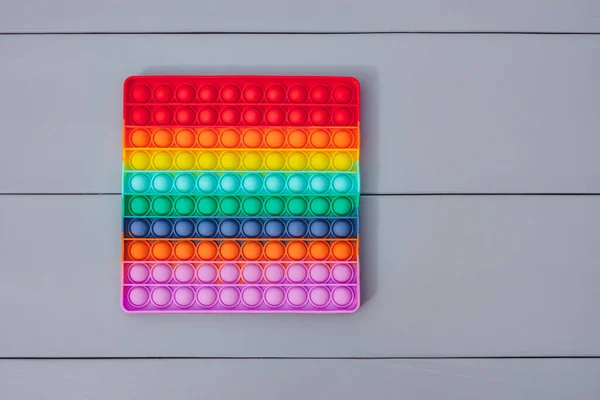 Parlak renkli silikon oyuncak. Yakın plan, Pop It. Popüler anti-stres oyuncağı. Gri bir arkaplanda