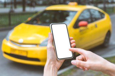Model, bir kızın elinde akıllı bir telefon var. Sarı bir taksinin arka planında.