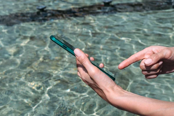 Yaklaş, Finger akıllı telefonun önünde. Temiz suyun arka planına karşı