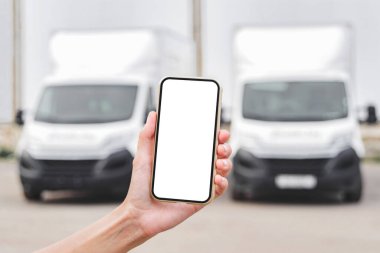 Kadın elinde akıllı telefon maketi. Kamyonların arka planına karşı. Lojistik kavramı