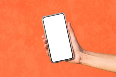 Yakın plan, bir kızın elindeki akıllı telefonun maketi. Dekoratif alçıdan yapılmış turuncu bir cephede