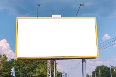Boş reklam panosu modeli. Şehir ulaşımının arka planına karşı güç şebekeleri ve gün batımından önce mavi gökyüzü